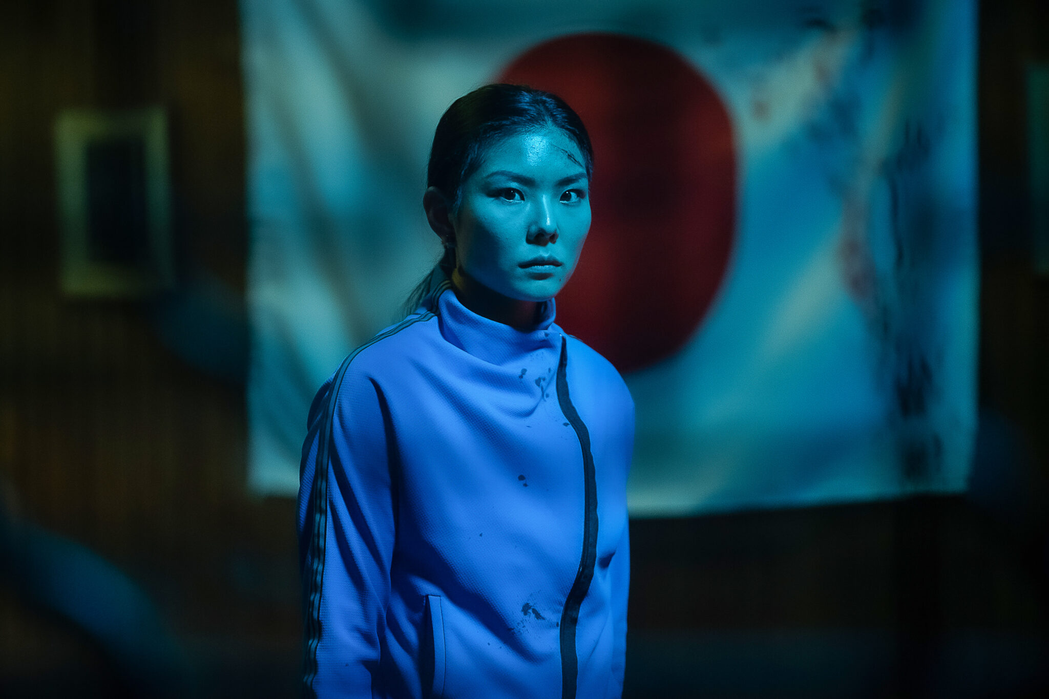 MASUMI im kalten Neonlicht. Im Hintergrund die japanische Flagge | Yakuza Princess