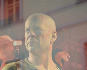 Bruce Willis in Stirb Langsam 5, am linken Rand eine Fotographin mit Mütze und Kamera in der Hand