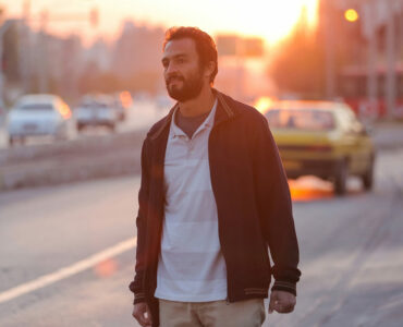 Amir Jadidi blickt in die Ferne. Er steht am Rande einer Autobahn, die Sonne geht gerade unter