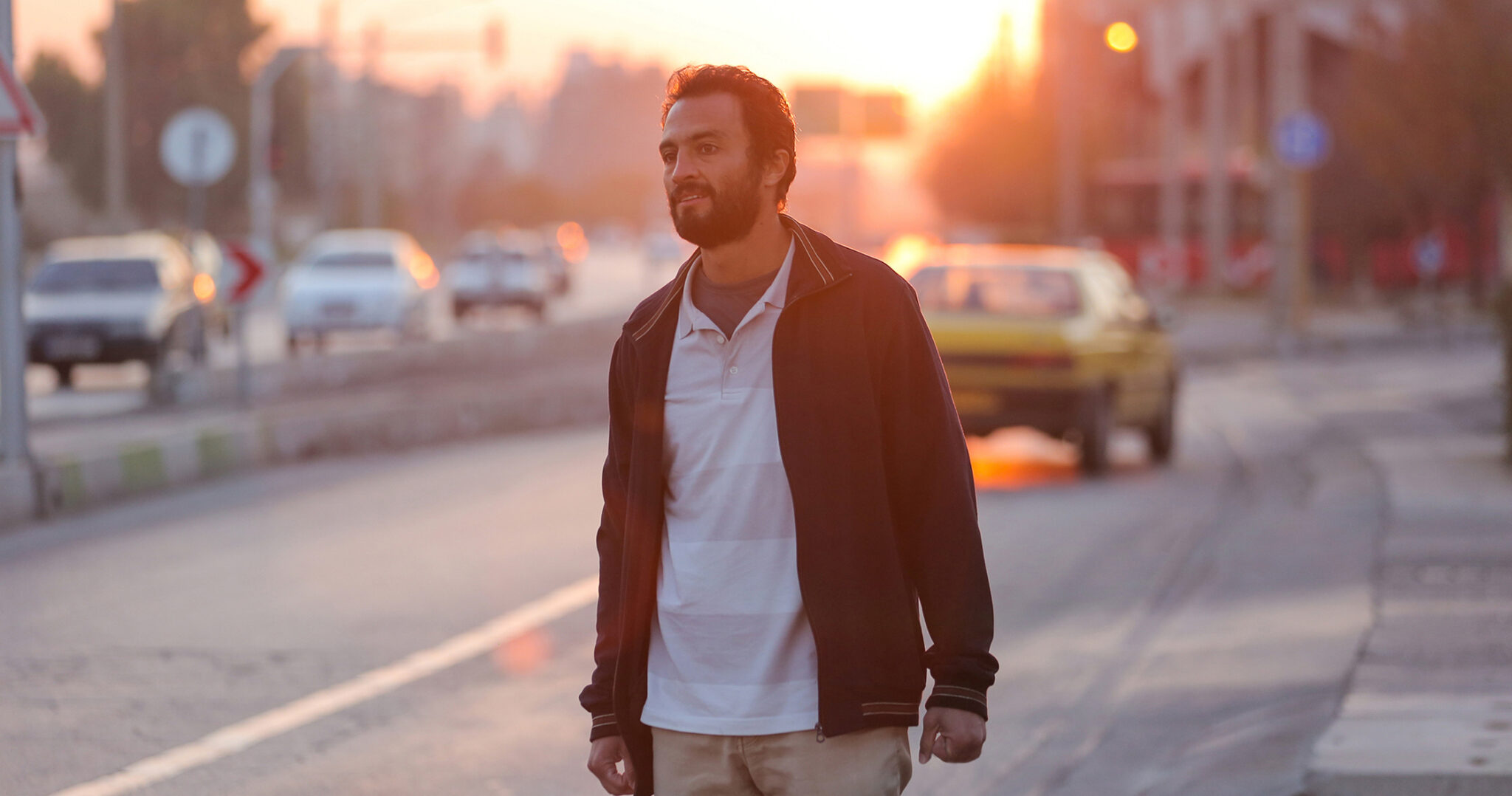 Amir Jadidi blickt in die Ferne. Er steht am Rande einer Autobahn, die Sonne geht gerade unter - A Hero - Die verlorene Ehre des Herrn Soltani