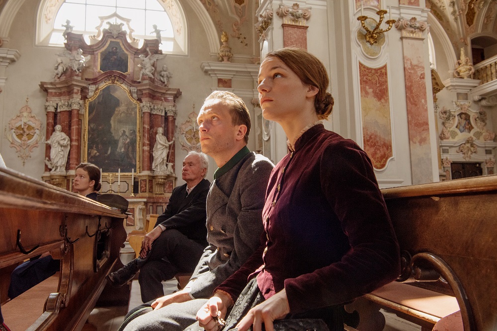 Franz (August Diehl) und Franziska Jägerstätter (Valerie Pachner) sitzen nebeneinander in der Kirche in Ein verborgenes Leben.