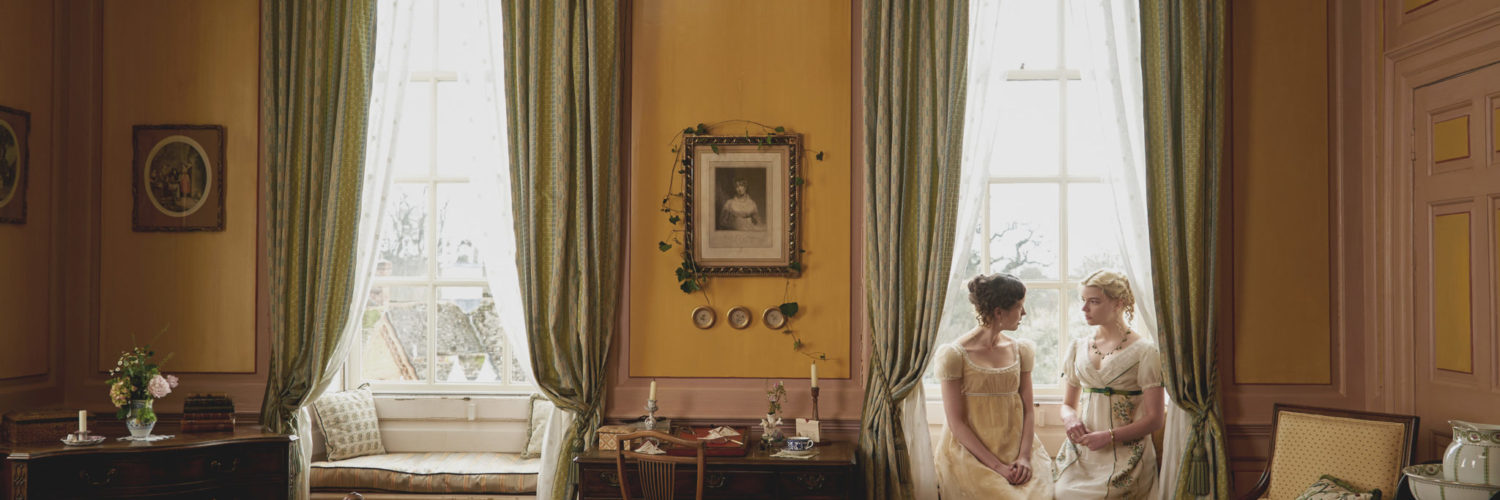 Emma, gespielt von Anya Taylor-Joy, und Harriet, gespielt von Mia Goth, sitzen am rechten Bildrand auf der Fensterbank von Emmas Schlafzimmer.