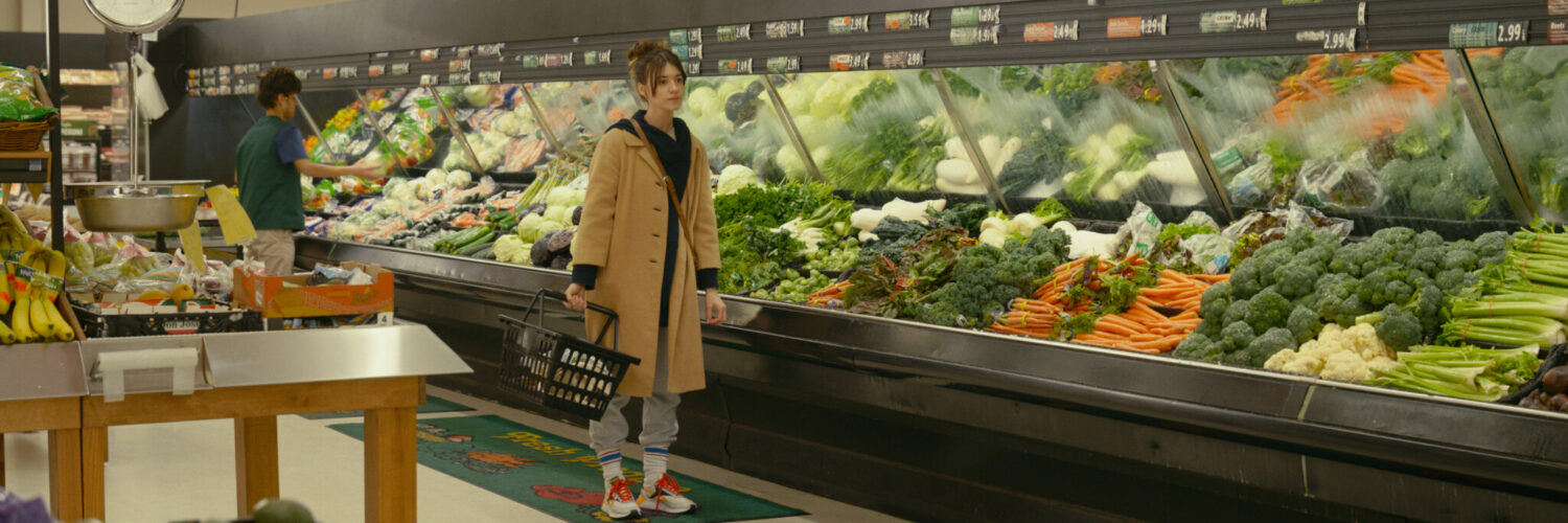 Eine Frau vor einer Gemüsetheke im Supermarkt