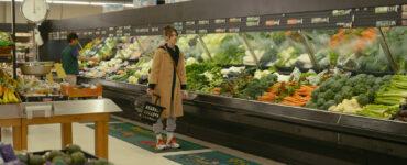 Eine Frau vor einer Gemüsetheke im Supermarkt