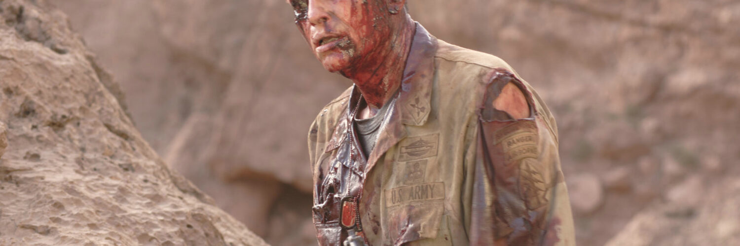 Ein Soldat steht blutüberströmt und mit klaffender Kopfwunde in der Wüste und trägt eine Pistole in The Hills Have Eyes 2