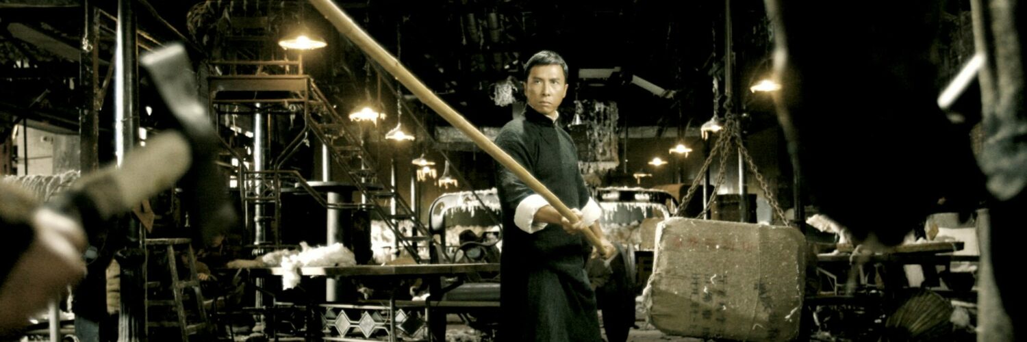 Donnie Yen steht in einer verlassenen Fabrik und hält einen langen Kampfstab in Händen - Die 15 coolsten Martial Arts Filme.