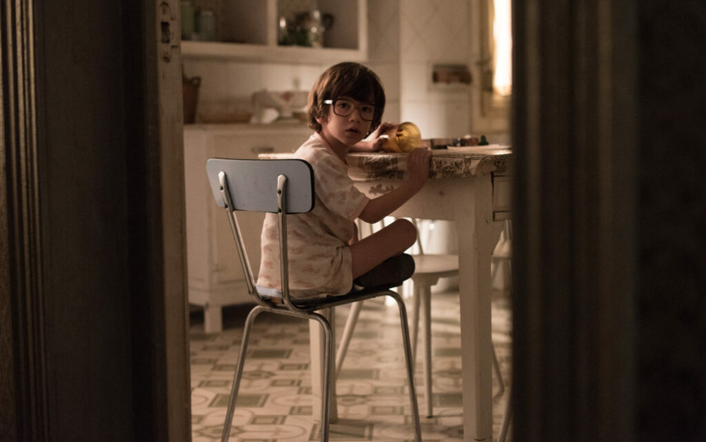Der kleine Sohne der Familie Rafael (Iván Renedo) sitzt auf einem Küchenstuhl und schaut über seine Schulter