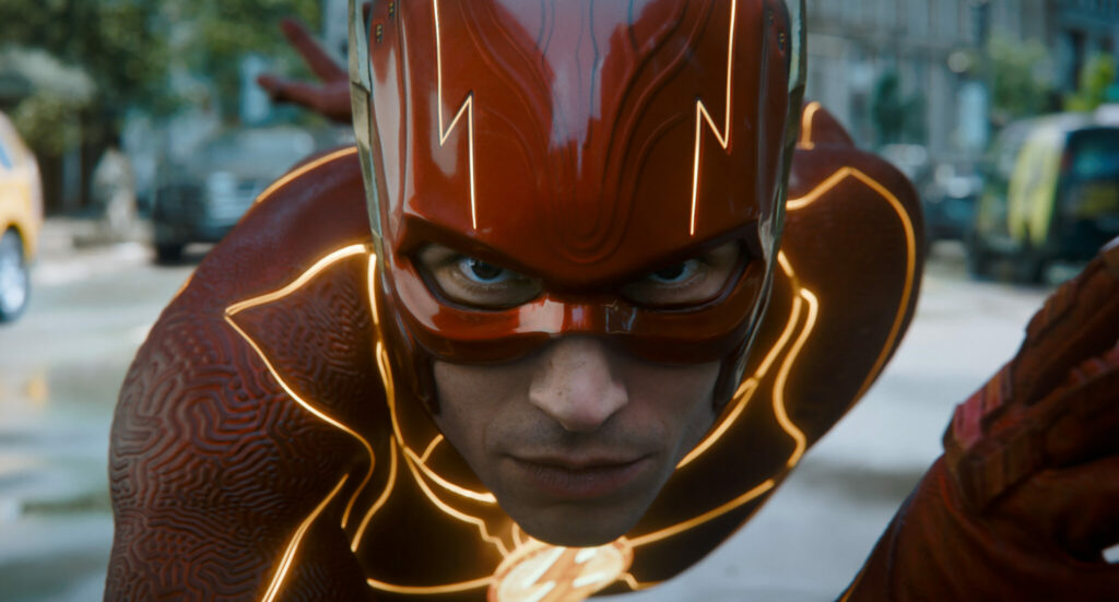 Der Schauspieleer Ezra Miller ist als The Flash zu sehen. Er trägt einen Anzug, der knallrot ist und orange leuchtende Linien zeigt.
