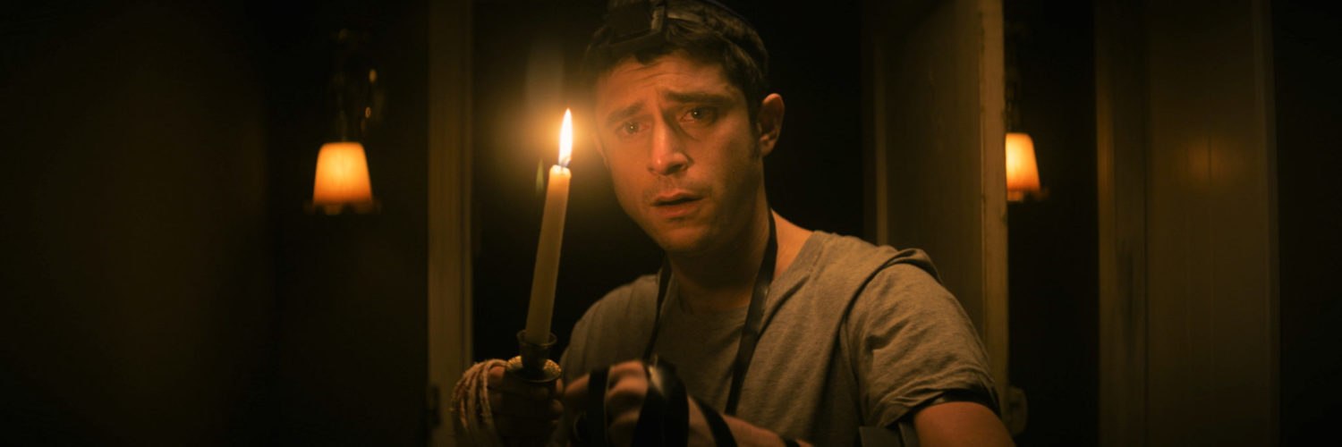 Yakov (Dave Davis) durchschreitet in THE VIGIL mit einer Kerze die Dunkelheit im mysteriösen Haus des Verstorbenen.