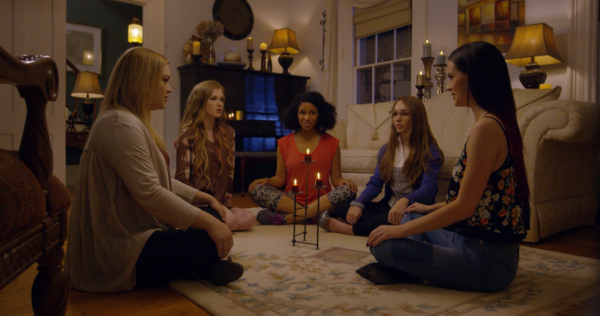 Eine Gruppe von fünf Mädchen sitzt in einem Zimmer im Kreis in The Witch Files.