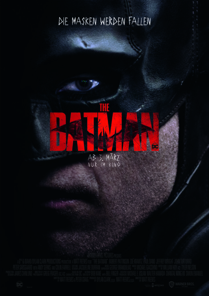Das maskierte Gesicht von Batman hinter dem Schriftzug The Batman in rot