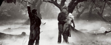 Der Wolfsmensch hält im nebligen, kargen Wald seine Geliebte Gwen, doch neben ihm erhebt sein Vater den Stock, um ihn zu töten - Universal Horror Filme